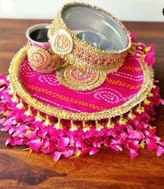 a pink and gold plate with some flowers on it, sitting on a wooden table