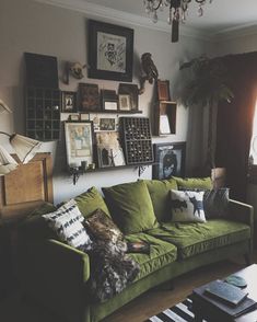 a living room with green couches and pictures on the wall above it's windows