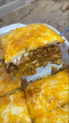 a white plate topped with meat and cheese enchilada covered in melted cheese