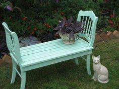 a small white cat sitting next to a bench and potted plant on the lawn