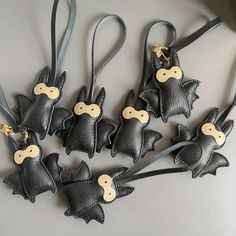 six black leather bats with wooden buttons on each one are hanging from a gray ribbon