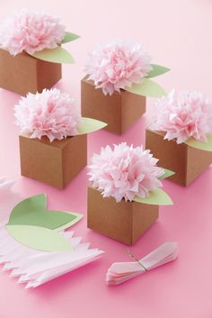 small boxes with paper flowers in them on a pink surface