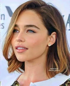 a close up of a person wearing a white shirt and gold jewelry on her neck