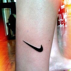 a black nike logo tattoo on the leg