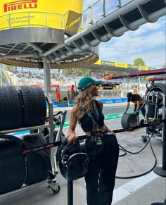 a woman in a green hat is at a gas station with some tires on the ground