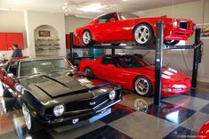 two cars are parked on top of each other in a garage with black and white checkered flooring