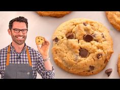 a man holding a cookie next to chocolate chip cookies