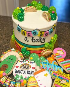 a decorated baby shower cake surrounded by cookies