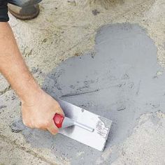 a person using a trowel to paint concrete