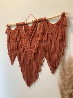 an orange wall hanging with tassels on it