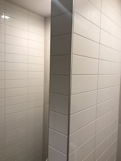 a bathroom with white tile walls and flooring next to a toilet paper dispenser