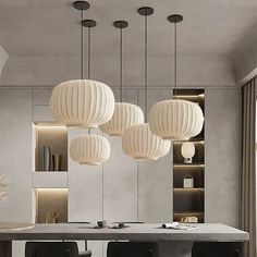 a modern dining room with black chairs and white lanterns hanging from the ceiling over the table