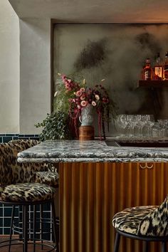 the bar is decorated with leopard print chairs and vases filled with flowers on top