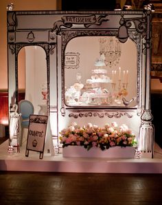 a table topped with lots of cake and flowers next to a mirror on the wall