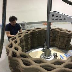 a man sitting in front of a machine made out of sandbags and roped together