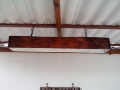 a wooden sign hanging from the side of a white wall next to a wood beam