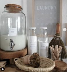 a wooden table topped with bottles and jars filled with liquid next to a brush, soap dispenser and other items