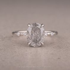 a pear shaped diamond ring with three stones on the band and an oval center stone