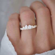 a woman's hand with a diamond ring on top of her finger, wearing a white lace dress