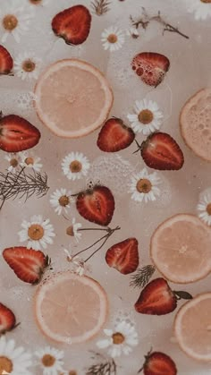 strawberries, oranges and daisies are floating in water with flowers on the surface