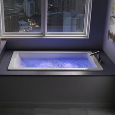 a bath tub sitting next to a window in a room with blue walls and tile flooring