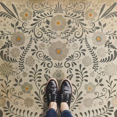 a person standing in front of a floral wallpaper pattern with their feet on the floor