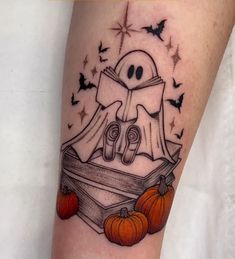 a tattoo with a ghost reading a book and pumpkins