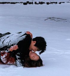 two people are laying in the snow and one person is holding his head over the other