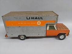 an orange and gray toy truck with a box on the back