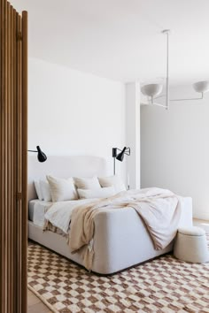 a large bed sitting in the middle of a bedroom next to a wall mounted light