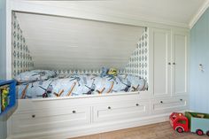 a child's bedroom with blue walls and white furniture, including a toy train bed