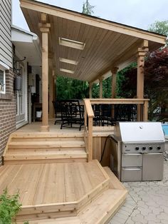 an outdoor kitchen and grill area with wooden steps leading up to the decking area