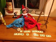 an elf sitting on top of a table next to two stuffed animals and scrabble letters