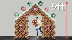 a man standing in front of an arch made out of balloons and candy canes