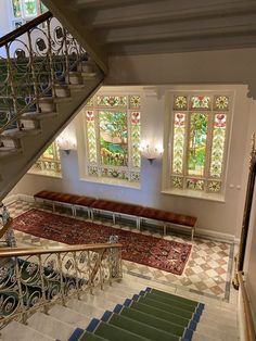 an ornate staircase with stained glass windows in the center and green carpet on the bottom