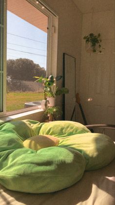 a green bean bag chair sitting on top of a bed in front of a window