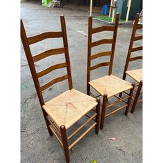 two wooden chairs sitting next to each other on the ground in front of a building