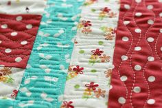 a close up view of a quilted table runner with white and red flowers on it