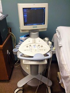 a hospital room with a monitor, bed and other medical equipment on the floor in front of it