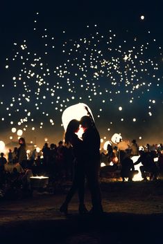 two people standing under an umbrella in front of fireworks