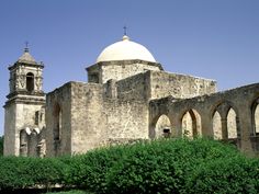 an old stone building with two towers and a white dome on top, surrounded by greenery