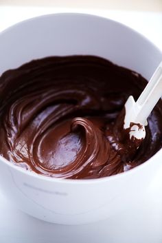 a white bowl filled with chocolate frosting on top of a table