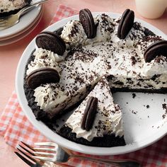 a pie with oreo cookies and cream on top sits on a checkered tablecloth