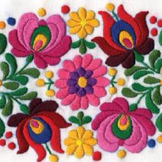 colorful flowers and leaves are embroidered on a white cloth with pom poms around the edges