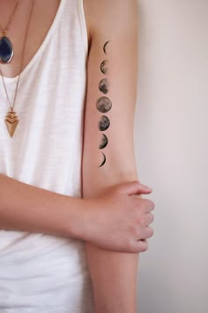 a woman's arm with five phases of the moon on it