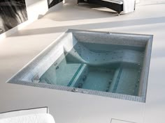 an indoor jacuzzi tub in the middle of a white tiled floored room