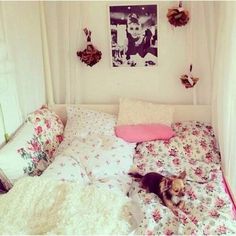 a small dog laying on top of a bed covered in white sheets and pink pillows