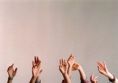 many people are reaching up to catch a frisbee in the air with their hands