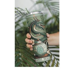 a person holding up a cup with a green dragon on it and palm trees in the background