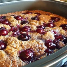 a close up of a pie in a pan with cherries on it and crumbs